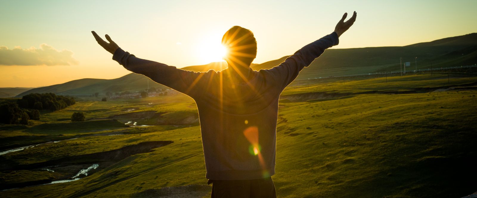 man holding arms up in mountain