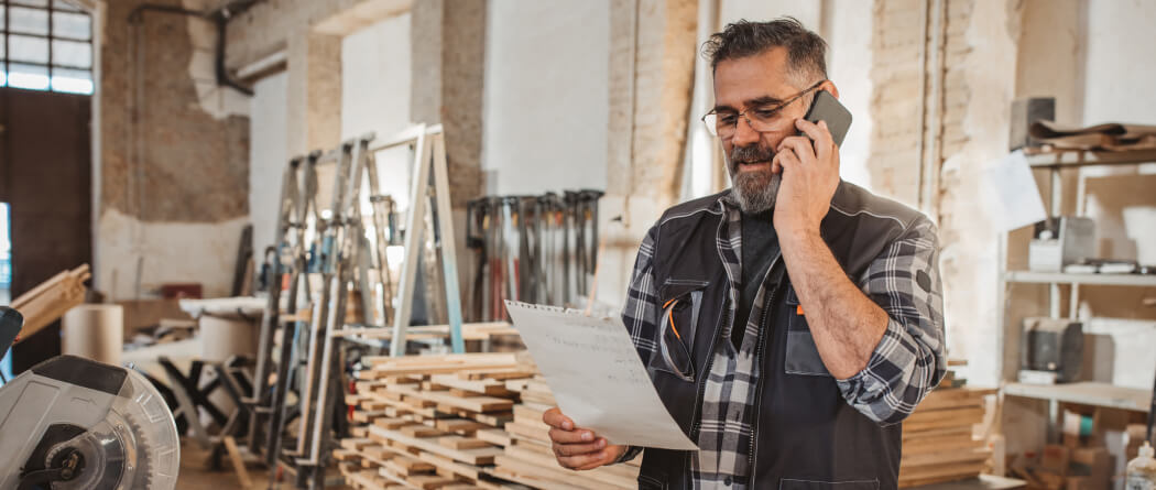 Man in a wood workshop talking on a phone