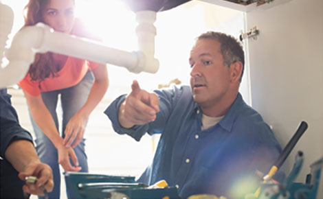 Plumber fixing pipe under sink