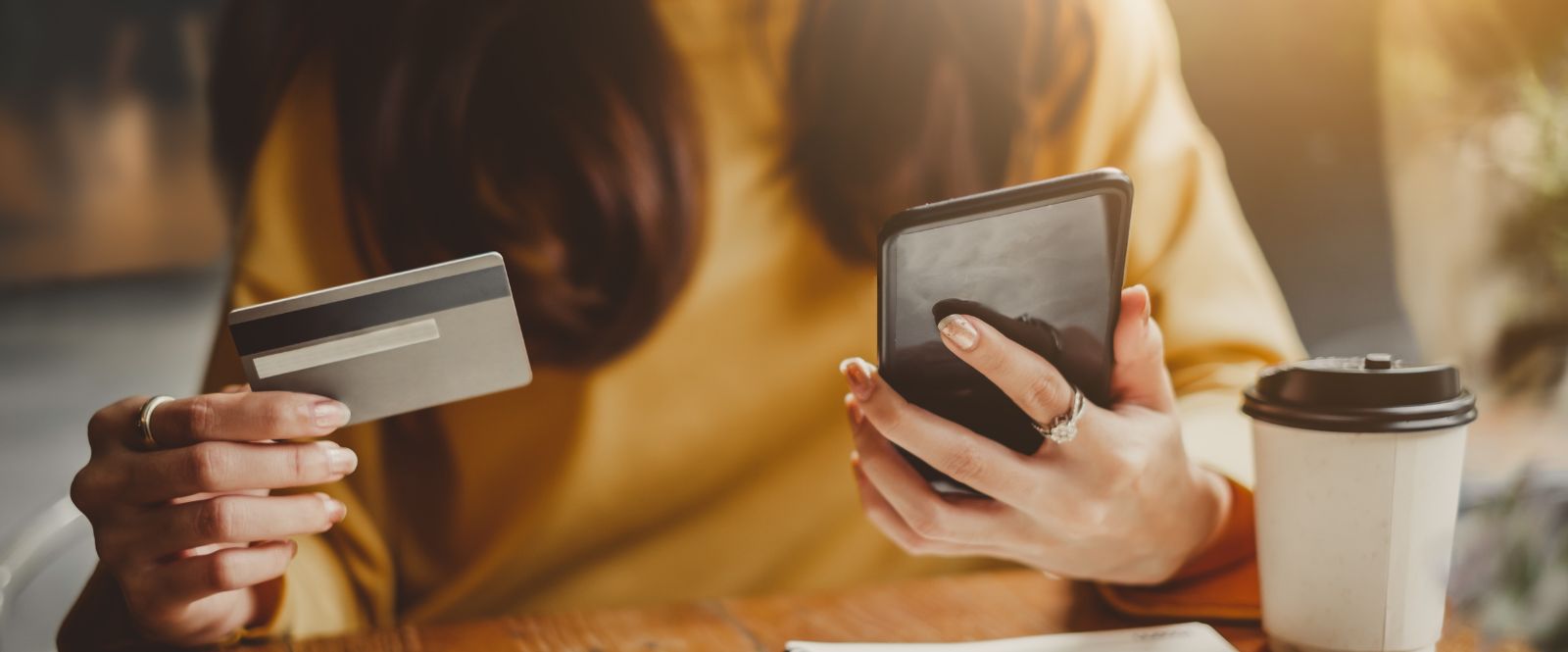 woman paying on a phone with coffee