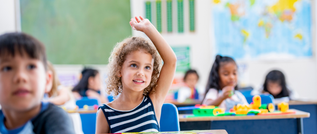 young girl raising hand in classroom