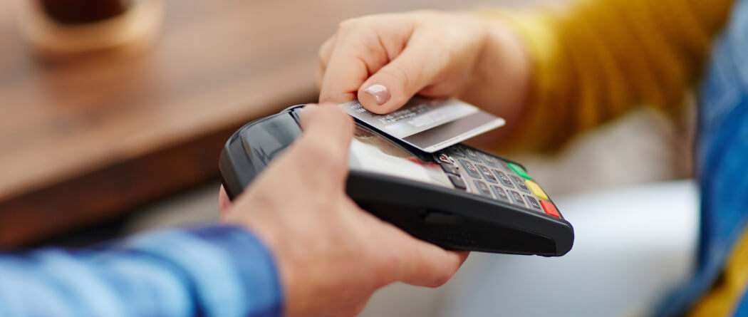 Close-up of a person holding a card up to a card payment reader