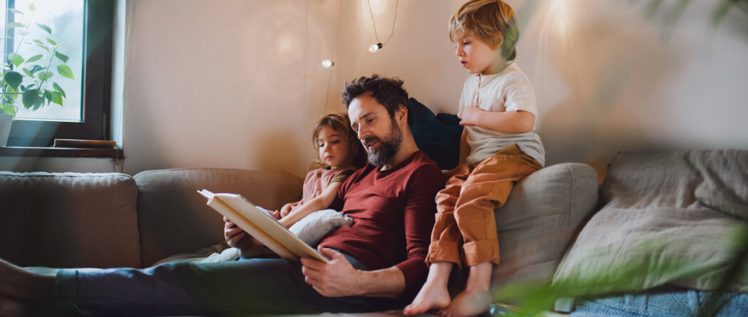 Dad and kids on a couch reading a book together