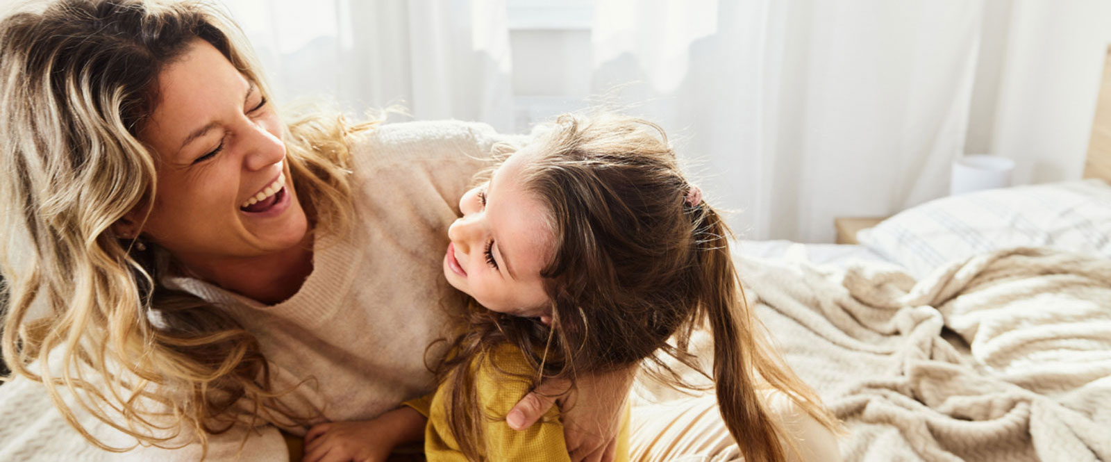 Mother and daughter laughing in bedroom